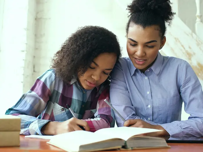 Two girls studying together at a table at home